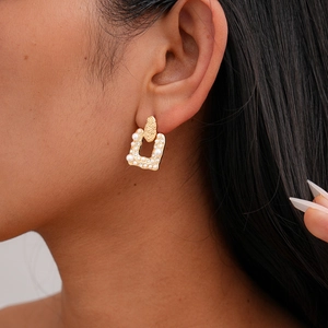 Detailed close-up of a vintage-style hammered gold earring with pearls and rhinestones
