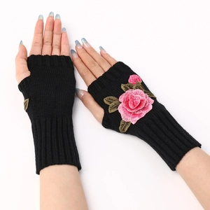 Detailed close-up of knitted fingerless gloves in black with pink rose embroidery
