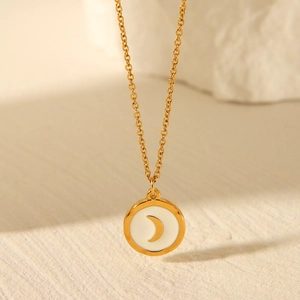 Macro shot of gold stainless steel necklace featuring a round moon pendant on white inlay