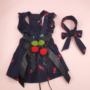 Detail of navy pet cherry dress and matching bow headband on a pink backdrop