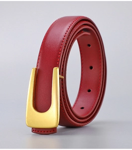 Detail of burgundy leather belt with matte gold U-shaped buckle and fine stitching