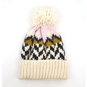 Macro detail of zigzag knit pattern and fluffy pompom on winter beanie hat