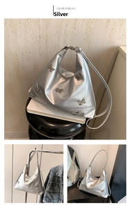 Detail view of silver hobo bag with metallic butterfly studs and sleek zipper closure