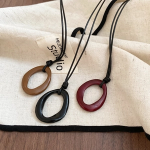 Gros plan de trois pendentifs ovales géométriques en émail marron, noir et rouge