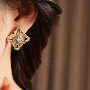 Close-up of vintage hollow flower stud earring with zircons worn on a model ear