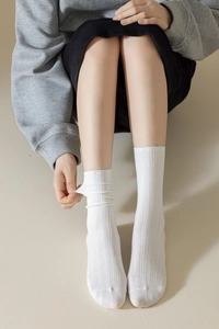 Détail des chaussettes blanches en coton côtelé montrant l'élasticité et la texture