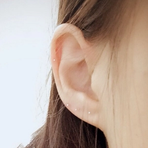 Minimalist silver stud earrings shown on a model for multiple ear piercings