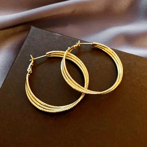 Detailed view of triple-layered golden hoop earrings with intricate beaded texture