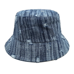 Close-up of distressed denim bucket hat with frayed edges and washed blue texture