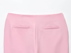 Dettaglio dei pantaloni svasati rosa che mostra il design della vita e le finte tasche a filo