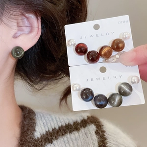 Détail de boucles d'oreilles en argent 925 avec perles en résine et effet oeil-de-chat