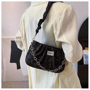 Detail of black pleated shoulder bag with unique silver floral chain and white logo label