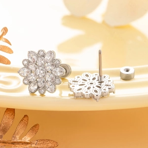 Silver flower stud earrings with sparkling cubic zirconia on a minimalist ceramic plate