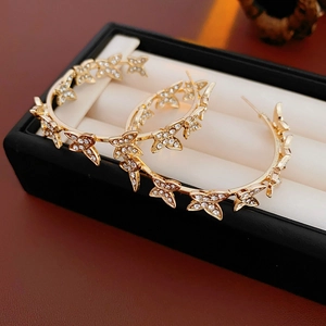 Vue détaillée de boucles d'oreilles créoles papillon dorées serties de strass brillants