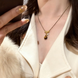 Close-up of a gold-plated tiger eye stone pendant necklace on a woman's collar