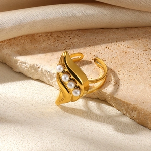 Detailed view of adjustable golden leaf ring with white pearls on a stone surface