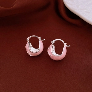 Macro detail of silver C-shape hoop earrings with pink enamel finish on red silk fabric