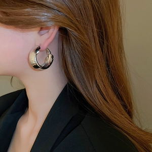 Close-up of polished silver-tone double-layer cross hoop earrings worn by a model