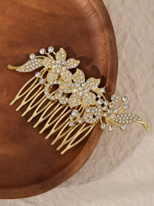 Detailansicht goldener Haarkamm mit weißen Strassblumen auf einem Holztablett