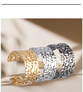 Detailed view of wide cuff bracelets with hammered texture in gold, silver, and gunmetal gray