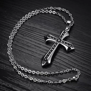 Retro silver cross pendant necklace with black dotted texture on a wooden background