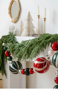 Close-up of 15cm Christmas baubles with red, green, silver stripes and pine needles