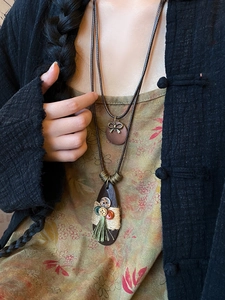 Detail view of a vintage Bohemian teardrop necklace with button and tassel accents.