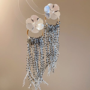 Macro detail of elegant flower stud with long dark grey beaded tassels and gold accents