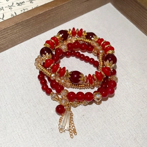 Detailed macro of red crystal beads and golden floral spacers on multilayered bracelet