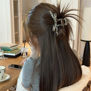Silver metal butterfly hair claw clip with grey leopard pattern shown in use on long hair