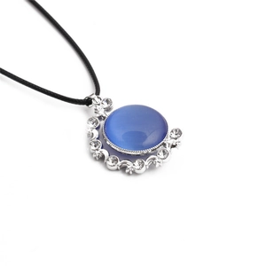 Detail of round blue cat eye stone pendant with silver moon and star crystal accents