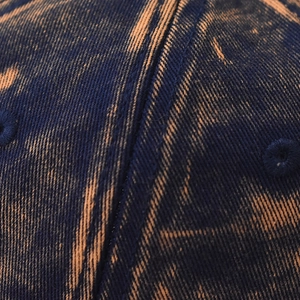 Macro detail of acid washed blue denim fabric with orange texture and double stitching