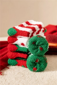 Close-up of festive coral fleece Christmas socks with red and white stripes and polka dots
