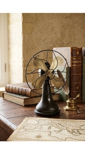 Detail of vintage industrial decorative fan on wooden desk with antique books and map