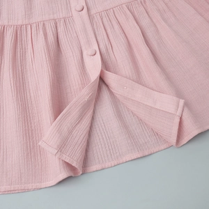 Close-up of pink fabric texture featuring delicate pleats and matching covered buttons