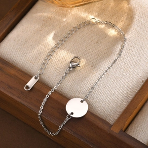 Detailed close-up of a silver stainless steel chain bracelet with a round blank charm