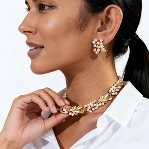 Detail of vintage gold-tone leaf and pearl necklace set worn on a female model