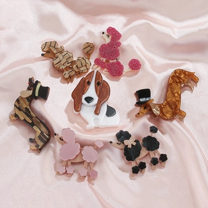Detail of elegant dog brooches with textured finish on a soft pink satin background