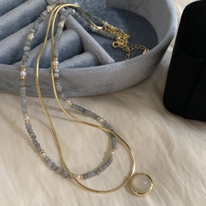Close-up of double-layer necklace with blue stone beads and gold moonstone pendant