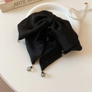 Detail of a black bow hair claw clip with silver sequins and grey transparent bead pendants
