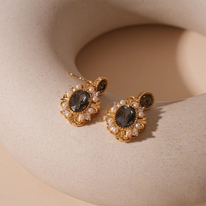 Macro shot of vintage gold earrings with grey oval stone and pearl in ceramic decor