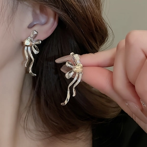 Detail of silver bow tassel earring with champagne heart stone on female ear
