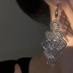 Detail view of long silver tassel earrings with geometric hollow rhombus mesh layers