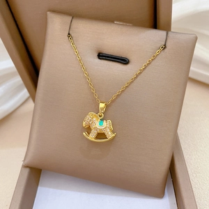 Detail of gold titanium horse pendant with white crystals and cyan enamel inlay