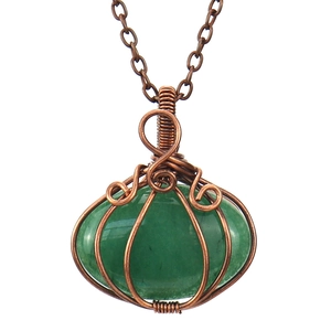 Detail of handmade copper wire-wrapped green natural stone pumpkin shaped pendant