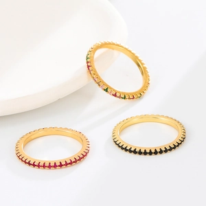 Détail de trois bagues dorées ornées de zircons rouges, noirs et multicolores