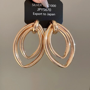Gros plan de boucles d'oreilles pendantes ovales doubles dorées sur carte noire