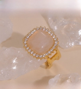 Macro detail of gold PVD plated ring with square pink zircon and crystal ice background