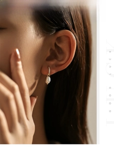 Close-up of gold baroque pearl hoop earrings on model with sparkling pavé details