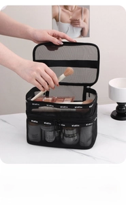 Detail of black double-layer mesh makeup bag with brushes and skincare products